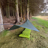 DD SuperLight Bikepacker Tarp set up in forest over a green sleeping mat, ideal for outdoor adventures by DD Hammocks.
